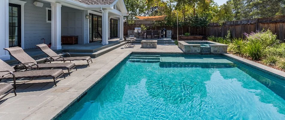 Pool in Bridgehampton, NY, with spa and lounge chairs.