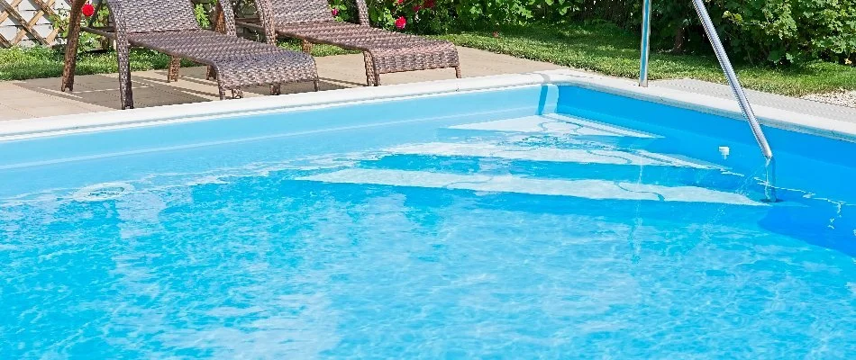 Swimming pool with two lounge chairs in Bridgehampton, NY.