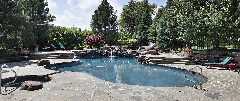 Trees around a pool in Bridgehampton, NY, with water feature.