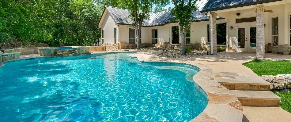 White house in Bridgehampton, NY, with a large tree and a pool.