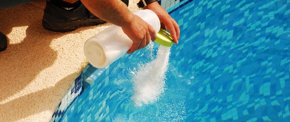 Person adding shock to a pool in Bridgehampton, NY.