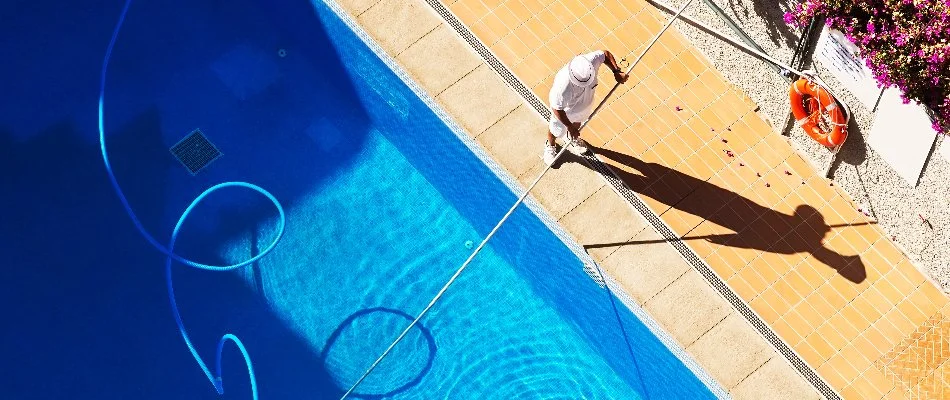 Person cleaning a pool on a property in Bridgehampton, NY.