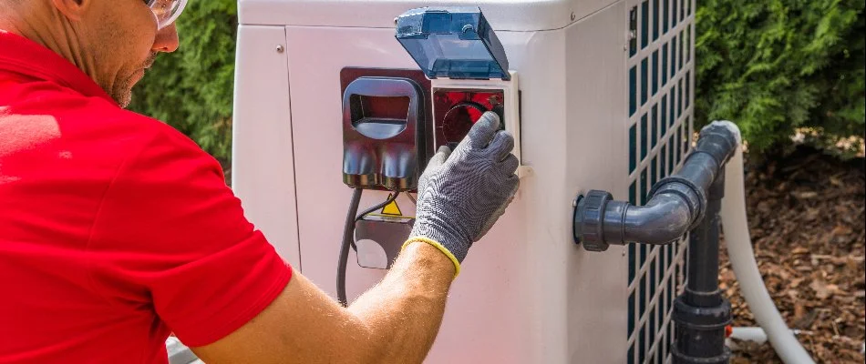 Worker repairing a pool heater on a property in Bridgehampton, NY.